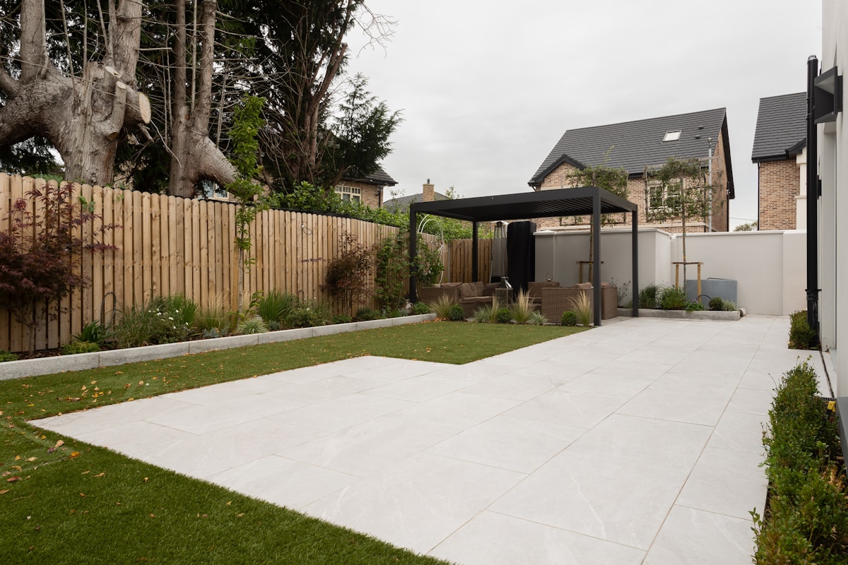 Tuin met houten schutting, gazon en overkapping